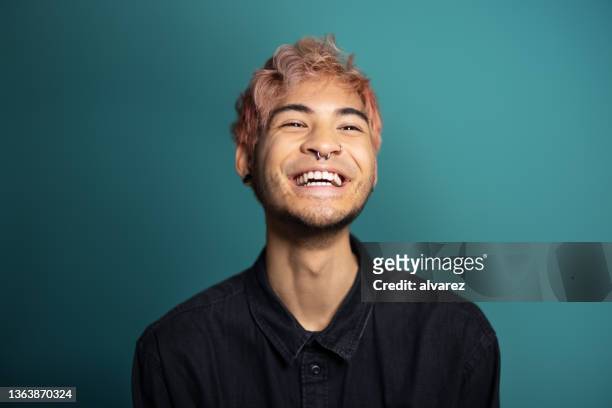 fröhlicher junger mann, der auf blauem hintergrund lächelt - kopfbild stock-fotos und bilder