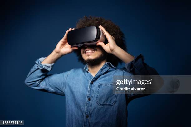 young man using vr glasses on blue background - vr glasses bildbanksfoton och bilder