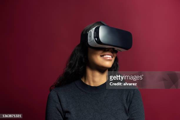 junge frau mit vr-brille auf rotem hintergrund - virtual reality simulator stock-fotos und bilder