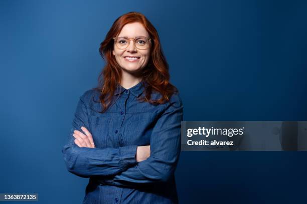 portrait of happy mature woman standing confidently - woman blue background stock pictures, royalty-free photos & images