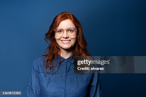 Portrait of a smiling mature woman with red hair on blue studio background Portrait of a smiling mature woman with red hair on blue studio background