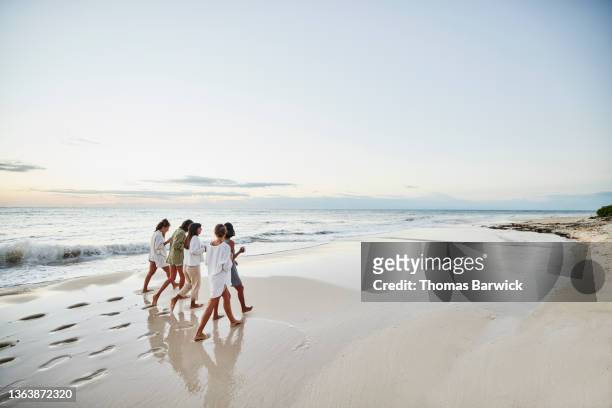 wide shot of female friends walking on beach at tropical resort at sunrise - beach trail stock pictures, royalty-free photos & images