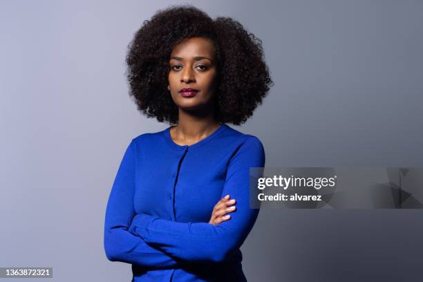 portrait en studio d’une femme confiante sur fond gris - visage sans expression photos et images de collection