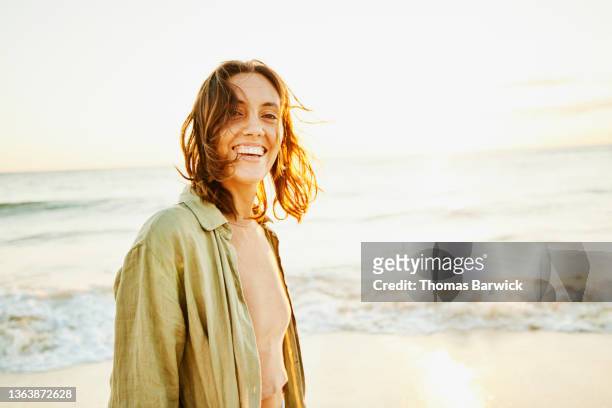 medium shot portrait of smiling woman on tropical beach at sunrise - natural shot female stock-fotos und bilder