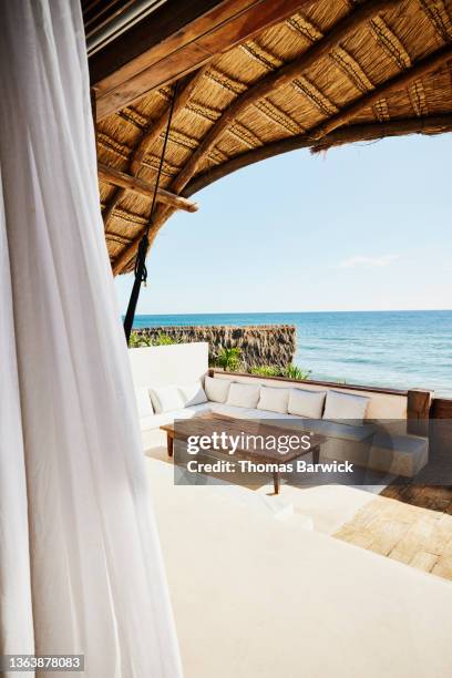 wide shot of sitting area on deck of luxury suite at tropical resort looking over ocean - curtain hotel stock-fotos und bilder