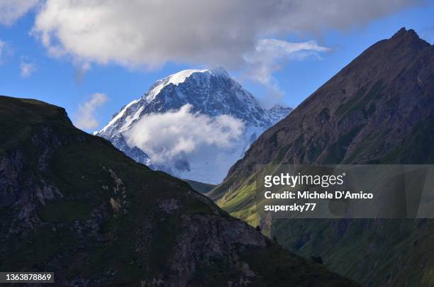 the mighty summit of mont blanc emerging between two steep mountains - mont blanc massiv stock-fotos und bilder