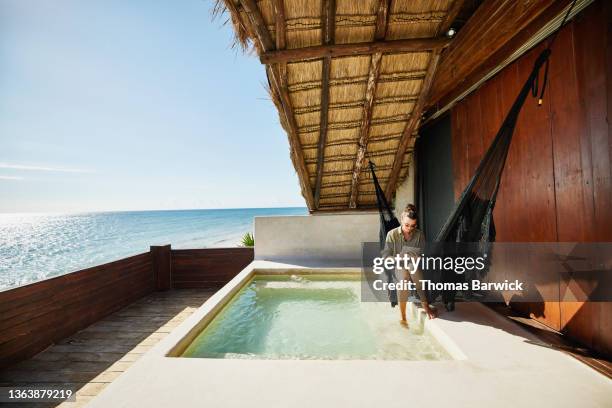 wide shot of woman working on digital tablet in hammock next to pool on deck of luxury suite at tropical resort - business person ipad travel stock-fotos und bilder