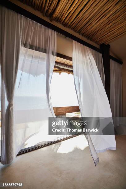 wide shot of curtains blowing in wind in luxury suite at tropical resort - curtain blowing stock pictures, royalty-free photos & images