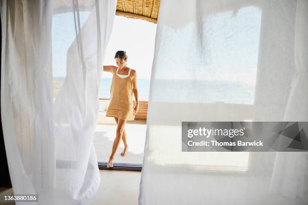 wide shot of woman walking through curtains on deck of luxury suite at tropical resort - person of the year honoring caetano veloso roaming inside stockfoto's en -beelden