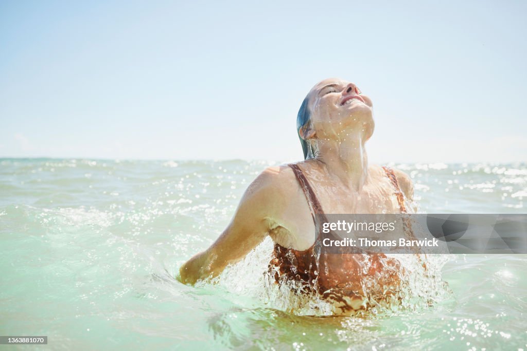 Medium wide shot of smiling woman emerging from ocean