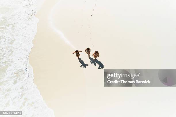 wide shot overhead view of female friends walking on tropical beach - aerial beach people stock pictures, royalty-free photos & images