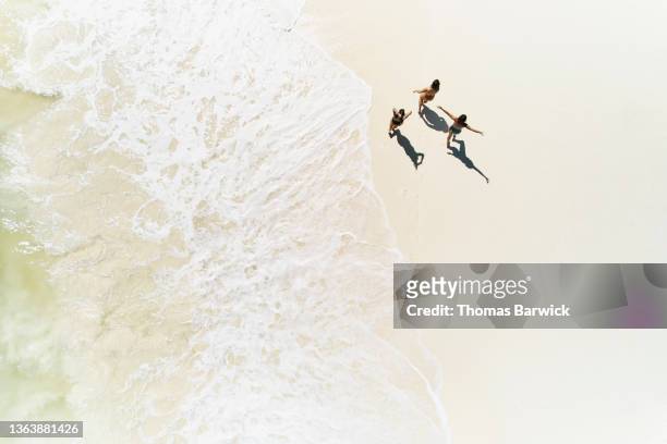 extreme wide shot overhead view of female friends walking on tropical beach - choicepix photos et images de collection