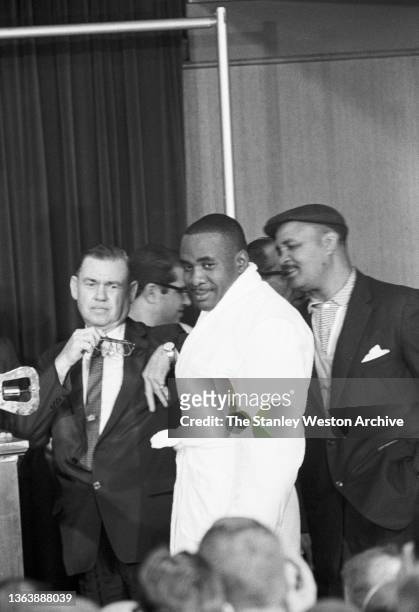Photo shows Sonny Liston at the Sheraton Hotel in Chicago smiling for the media while approaching the scale for his pre-fight weigh-in for his bout...