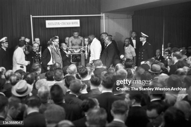 Pre-fight Weigh-in - Photo shows Floyd Patterson weighing-in on the scale, Sonny Liston observing Patterson's weight, and Muhammad Ali keeping a keen...