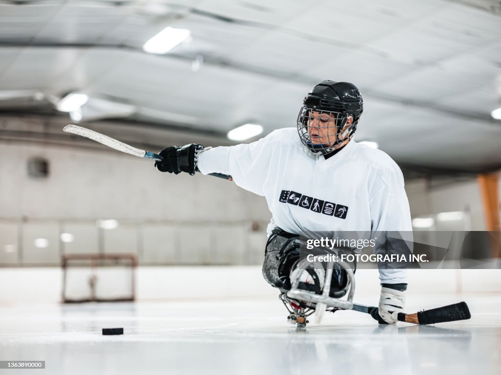 Mature Disabled Latin woman playing sledge hockey