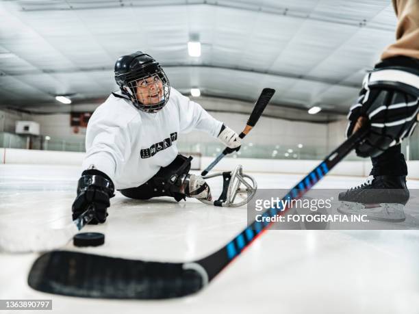 mature disabled latin woman and her trainer practising sledge hockey - ice hockey coach stock pictures, royalty-free photos & images