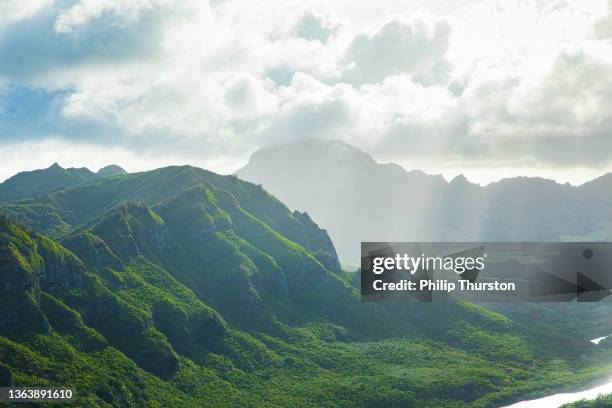 nubes que se ciernen sobre la exuberante cordillera verde hawaiana en la luz dorada del atardecer - big island hawaii islands fotografías e imágenes de stock