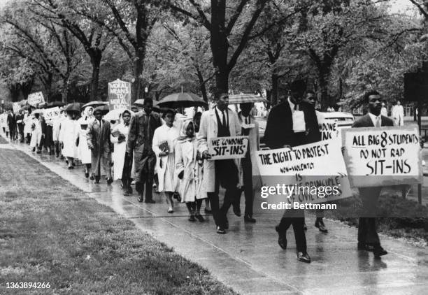 Sixty Black students marched through the Kansas University campus today in a protest to a Big Eight student's resolution against sit-in...