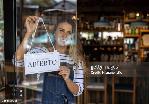 waitress hanging an open sign in spanish on the door at a restaurant - bar reopening stock pictures, royalty-free photos & images