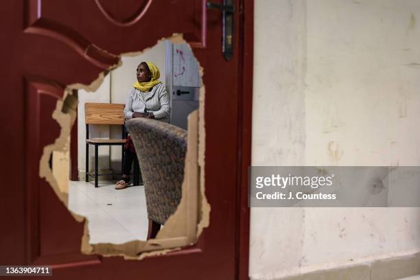 Woman can be seen sitting in the waiting room outside of Dr. Haimanot Ayele's office through a whole in the door damaged by the TPLF when they looted...