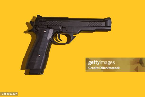 black gun with direct light and hard shadow on yellow background. murder, violence, gun, shooting, police, bodyguard, hitman and army concept. - armi foto e immagini stock
