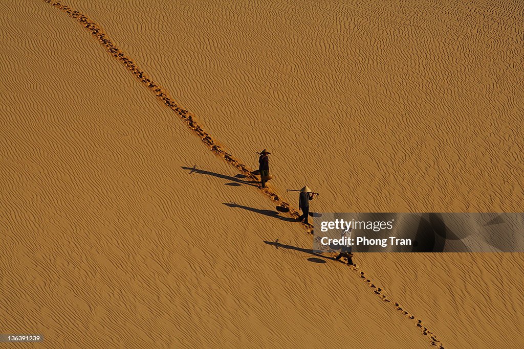 Three women walking on sand hill