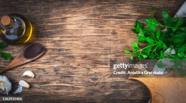 food background. top view of rustic kitchen table with wooden cutting board, cooking spoon, olive oil, parsley and garlic. - planche à découper bois photos et images de collection