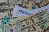 1040 Tax form with refund check and currency US dollar banknotes close-up