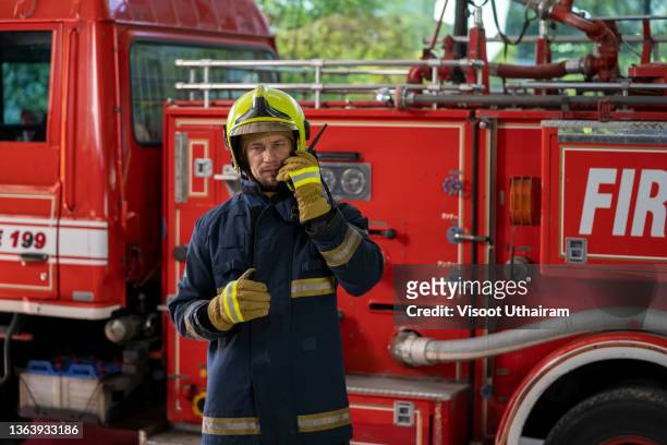 fireman in a protective uniform standing next to a fire truck and talking on the radio. - australia fire ストックフォトと画像