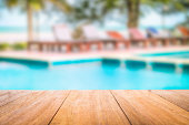 Wooden table with the swimming pool blurred background