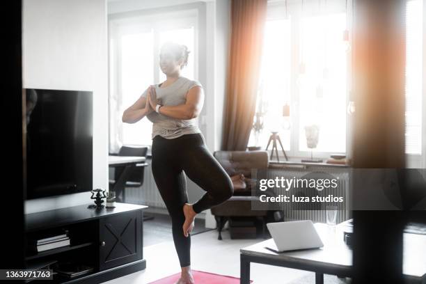 practicar yoga en la sala de estar - standing on one leg fotografías e imágenes de stock