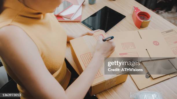 asian woman packing a package box at home prepare to sending to customer. - closing laptop stock pictures, royalty-free photos & images