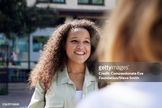 smiling businesswoman talking with coworker in city - differential focus stock pictures, royalty-free photos & images