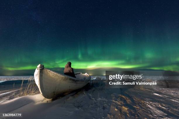 man watching the sky on a rowboat during northern lights, hailuoto, finland - oulu finland stock pictures, royalty-free photos & images