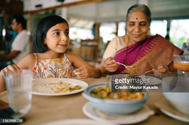 girl and grandmother eating noodles in a restaurant - indian family vacation stock pictures, royalty-free photos & images