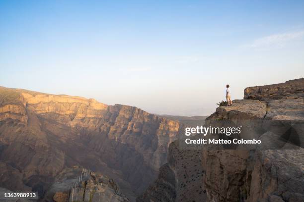 man standing on the edge of canyon, jebel shams, oman - oman foto e immagini stock