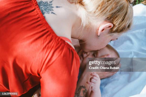 mother kissing baby boy laying down on white sheet. - good night kiss - fotografias e filmes do acervo