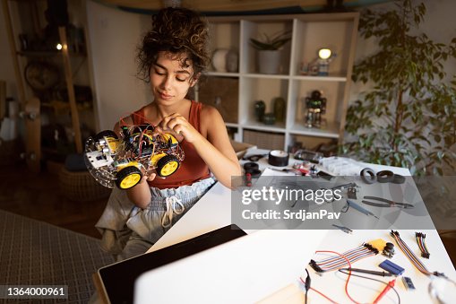 Focused student of robotic engineering and programmer analyzing all cables and inputs, while following steps on open-source hardware and software platform Focused student of robotic engineering and programmer analyzing all cables and inputs, while following steps on open-source hardware and software platform