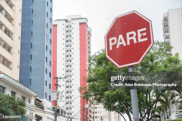 a stop sign in portuguese on a city street with tower blocks in the background - portuguese culture stock pictures, royalty-free photos & images