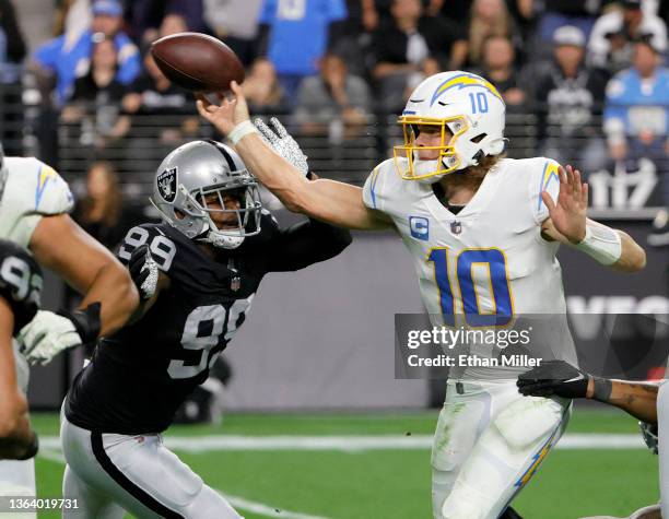 Quarterback Justin Herbert of the Los Angeles Chargers throws under pressure from defensive end Clelin Ferrell of the Las Vegas Raiders during their...