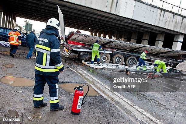 Firefighters and members of a repair service work after a lorry drove off a bridge on the E25 highway and crashed into the N678 road below in...