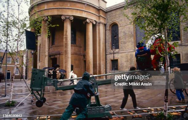 View of the cast and crew during an outdoor rain scene in the film 'Maurice' , London, England, December 1986.