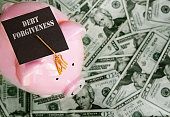 Piggy bank with Debt Forgiveness graduation cap on cash