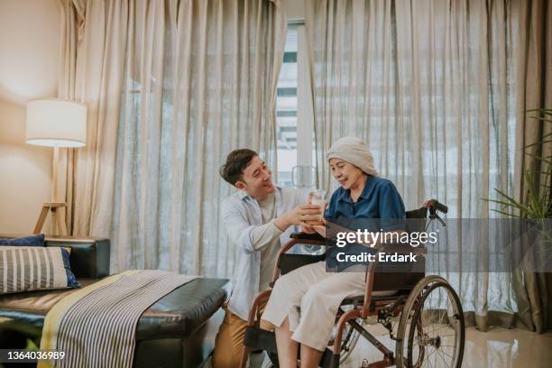 son giving a glass of milk to his mother on wheelchair. - milk family stock pictures, royalty-free photos & images