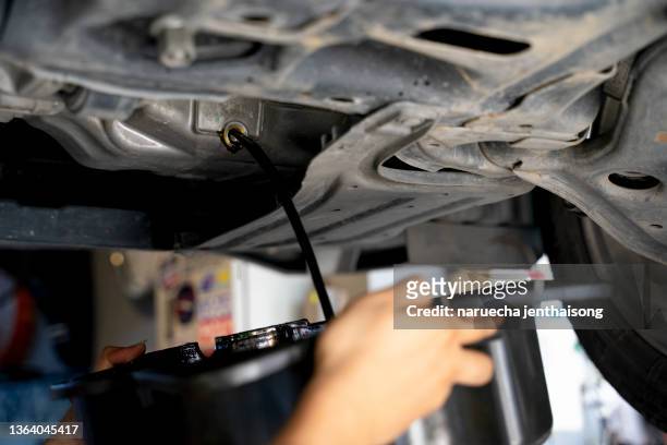 close-up of drains engine oil in a car during service. - car engine close up stock pictures, royalty-free photos & images