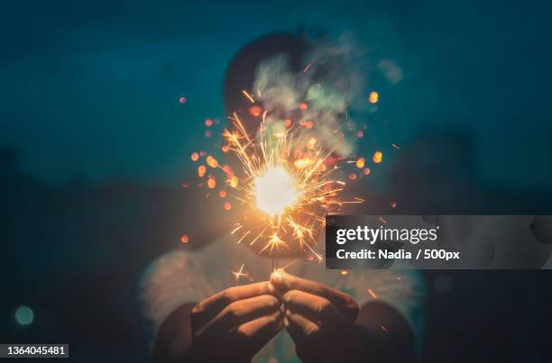 cropped hands holding sparkler at night,bangladesh - candela magica foto e immagini stock