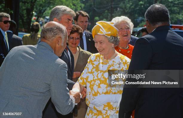 View of British monarch Queen Elizabeth II shakes hands as she visits a newly completed affordable housing project on Drake Place SE, Washington DC,...