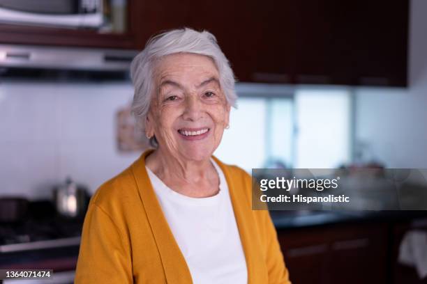 dolce donna anziana latinoamericana a casa di fronte alla telecamera sorridente con un sorriso dentato - woman smile kitchen foto e immagini stock