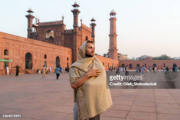 hombre caminando cerca de la mezquita en lahore por la noche - pakistan monument fotografías e imágenes de stock