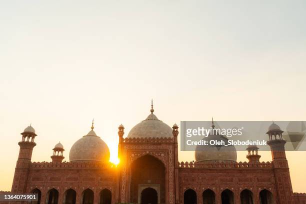 vögel fliegen bei sonnenuntergang über moschee in pakistan - blue mosque stock-fotos und bilder